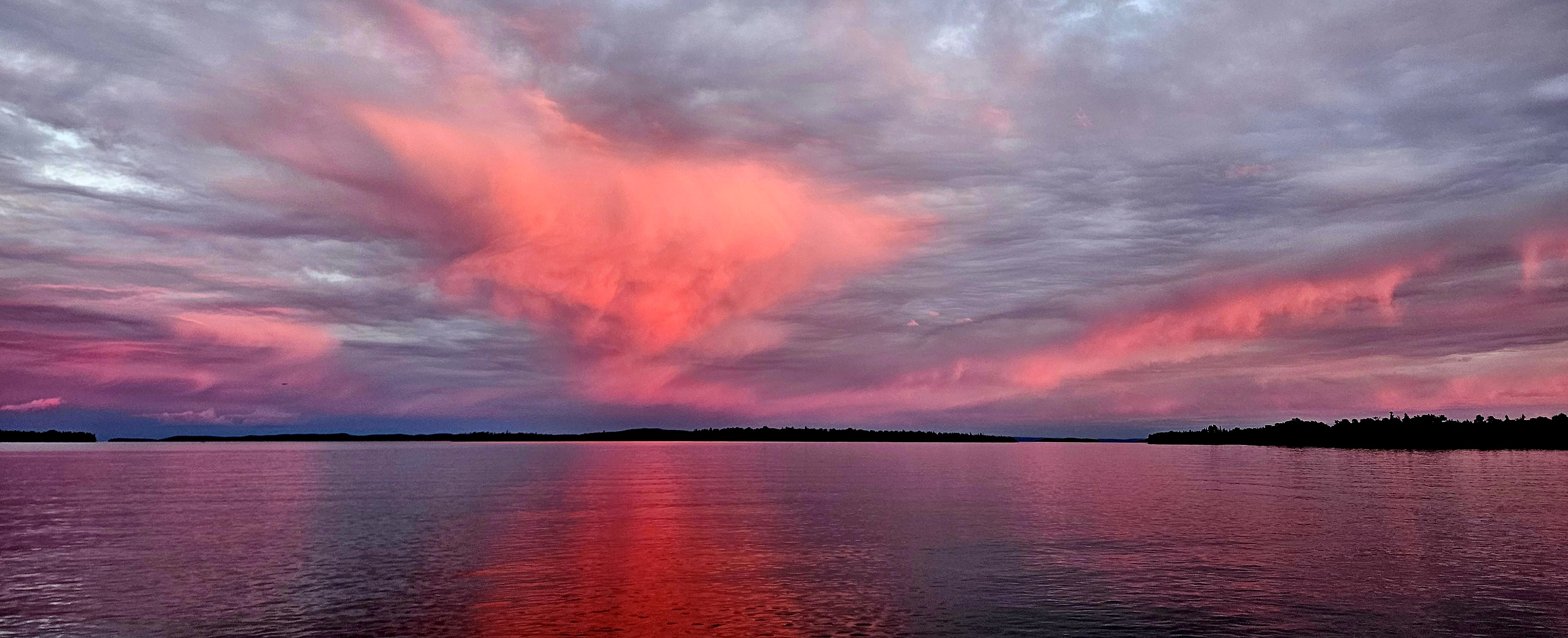 A beautiful red, blue and purple sunset is reflected in the water of Lake Superior.